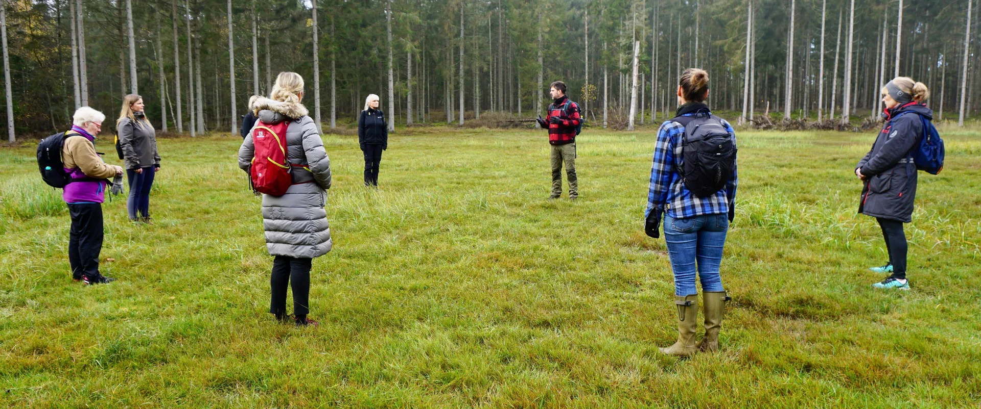 Deltagere i varme jakker på en lysning i skoven